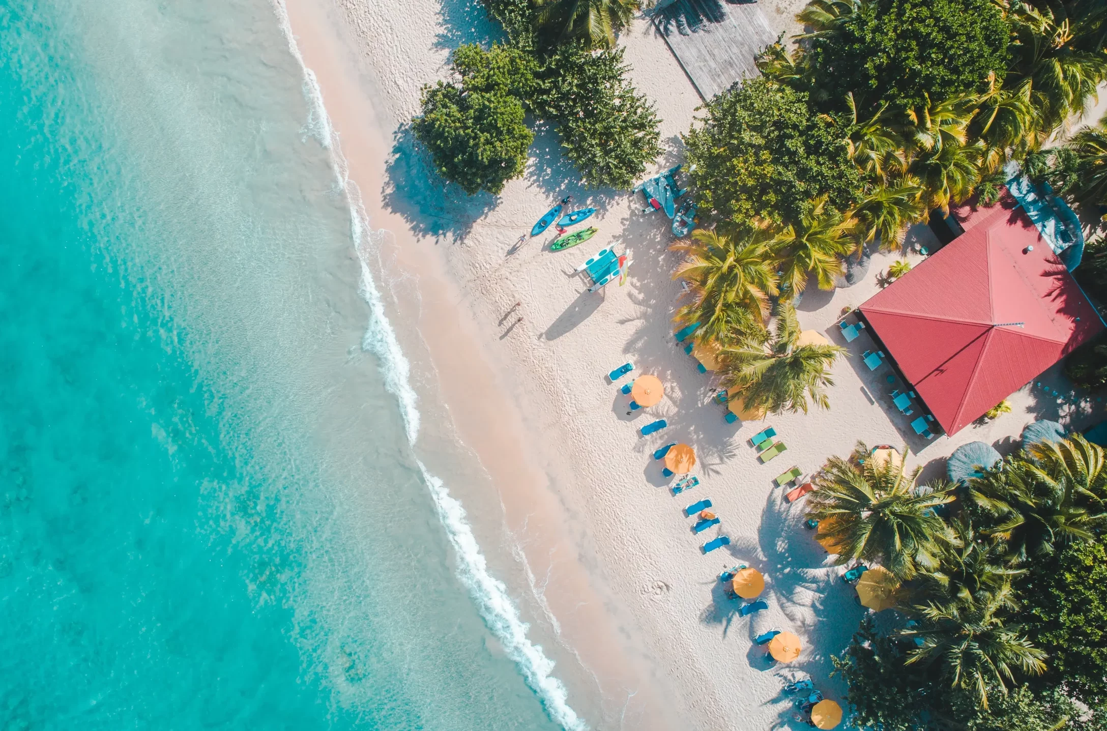 A travel advisor's aerial view of a beach with umbrellas and palm trees, perfect for trip planning.