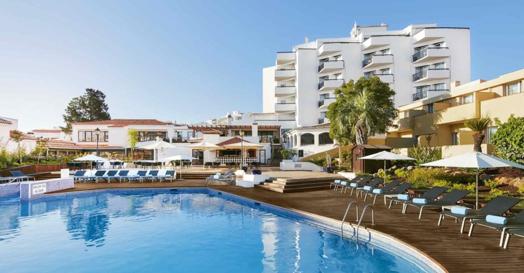 A hotel with a swimming pool and lounge chairs.